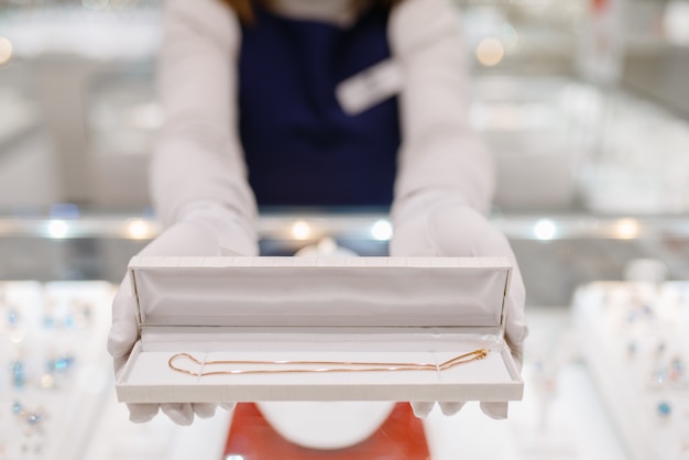 Female seller hands with gold bracelet in the case