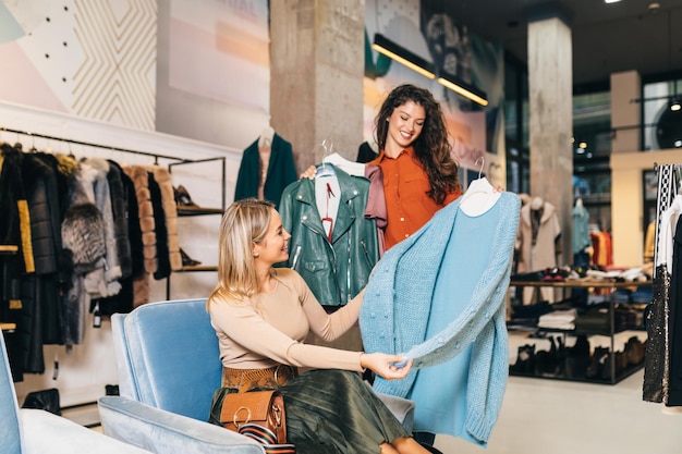 Female seller helps buyer to choose between different clothes.