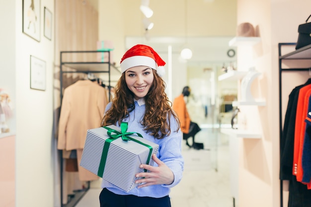 female seller offers a Christmas gift to a clothing store in Christmas clothes