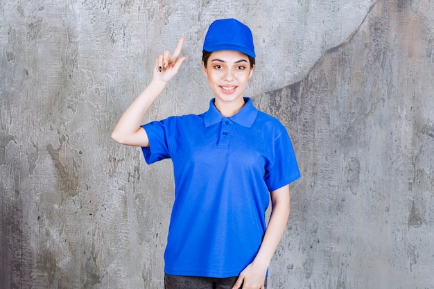 Female service agent in blue uniform pointing at above.