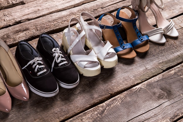 Female shoes on old floor. Tankette shoes and fabric keds. Footwear for every taste. From simplicity to luxury.