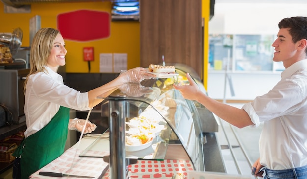 Foto proprietario del negozio femminile che serve panino al cliente maschio