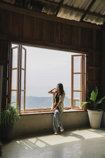 写真 木の窓に座る女性、くつろぎのコンセプト。