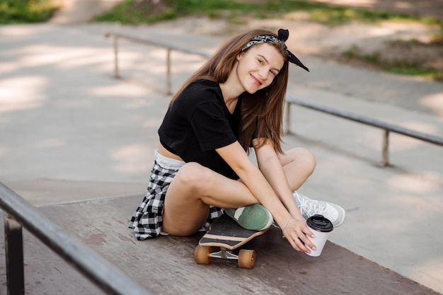 Female skater with a skateboard relaxing in the skating\
rink