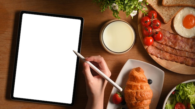 레시피 또는 메뉴를 위한 테이블 템플릿에 아침 식사 세트와 함께 디지털 태블릿에 스케치하는 여성