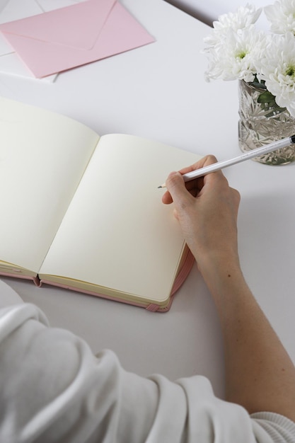 꽃이 있는 흰색 배경에 연필로 스케치북에 스케치하는 여성