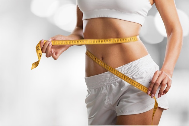 Female slender body in sport underwear holding orange on sea background