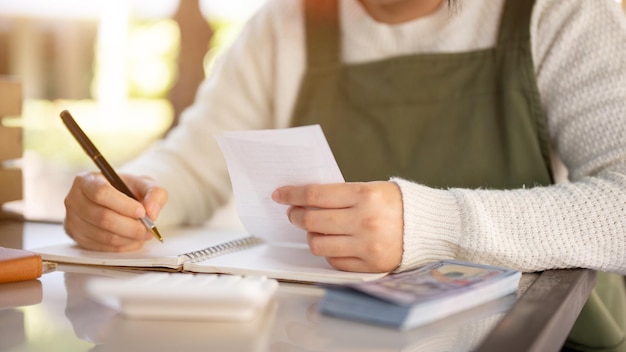 Photo a female small business owner calculating her monthly expenses checking bills receipts