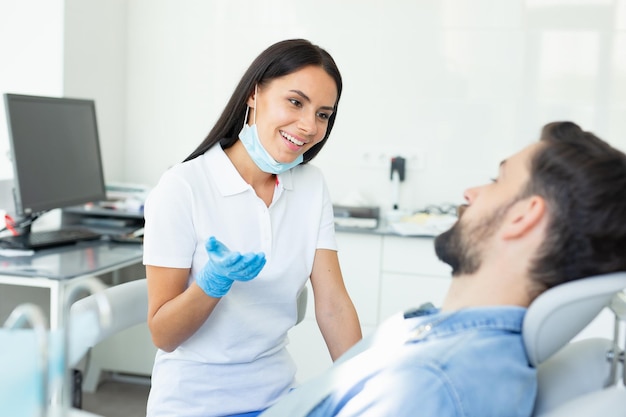 Dentista sorridente femminile talki dentista sorridente femminile che parla con il cliente maschio in hospitalng con il cliente maschio in ospedale