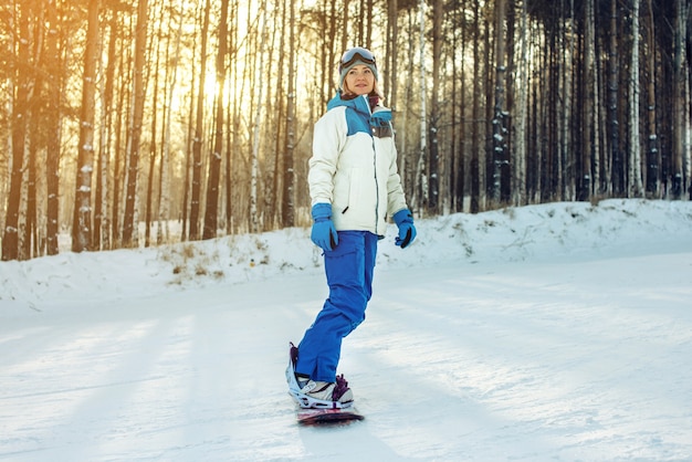 Female snowboarder snowboarding down the mountain