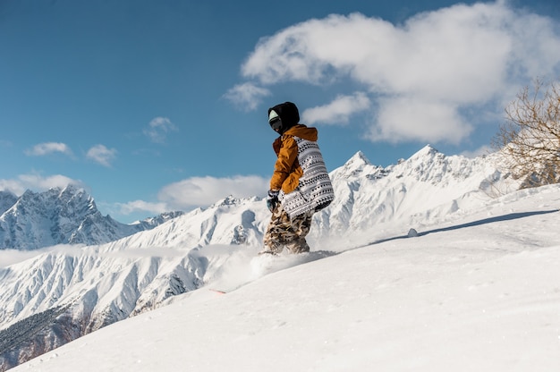 Female snowboarder in sportswear riding on the mountain slope