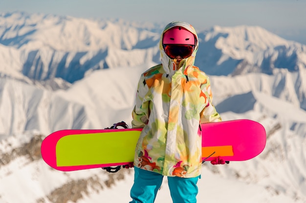 雪に覆われた山頂に立っているスポーツウェアの女性スノーボーダー