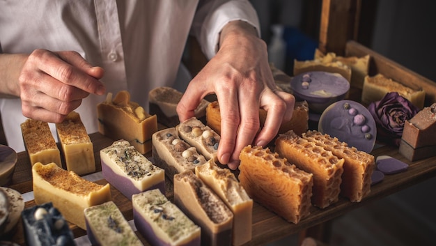 A female soap maker holds a piece of handmade soap A lot of different sliced pieces