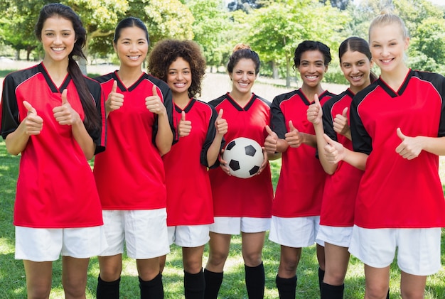 Female soccer team gesturing thumbs up at park