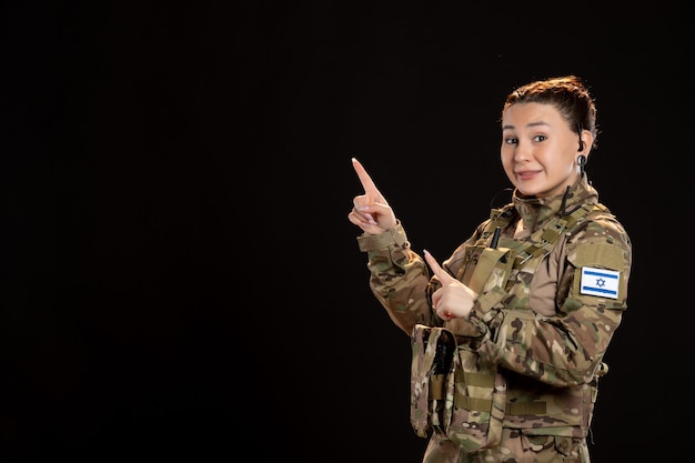 Female soldier in camouflage on black wall