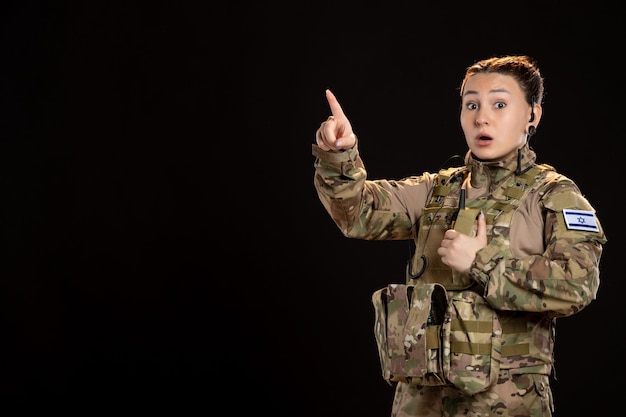 Female soldier in camouflage on black wall