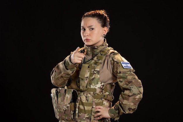 Female soldier in camouflage on black wall