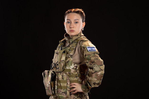 Female soldier in camouflage on black wall