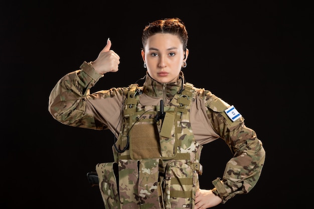 Female soldier in camouflage on black wall