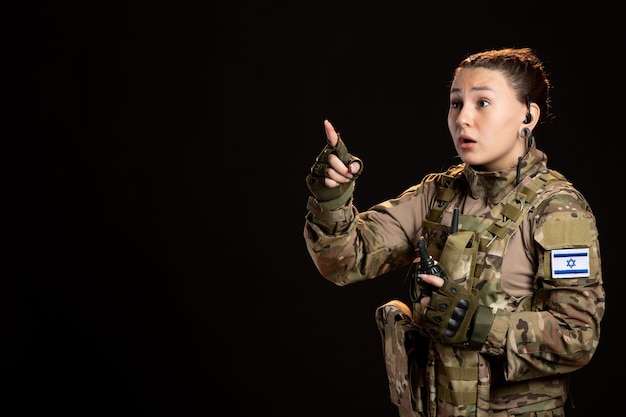 Female soldier in camouflage with grenade black wall