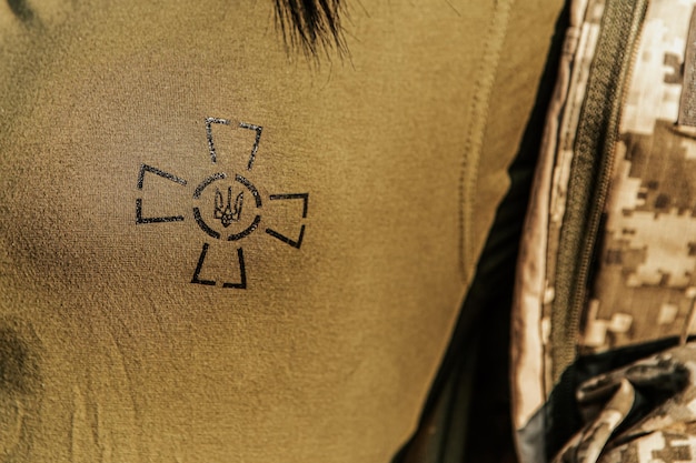 Female soldier dressed in military uniform and showing coat of arms of Ukraine state emblem