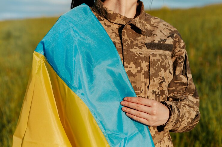 Женщина-солдат в военной форме, завернутая в украинский флаг