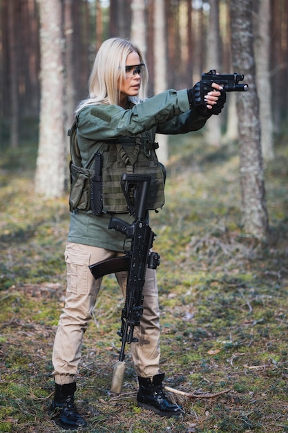 Photo female soldier takes aim from a tactical pistol in the forest vertical photography