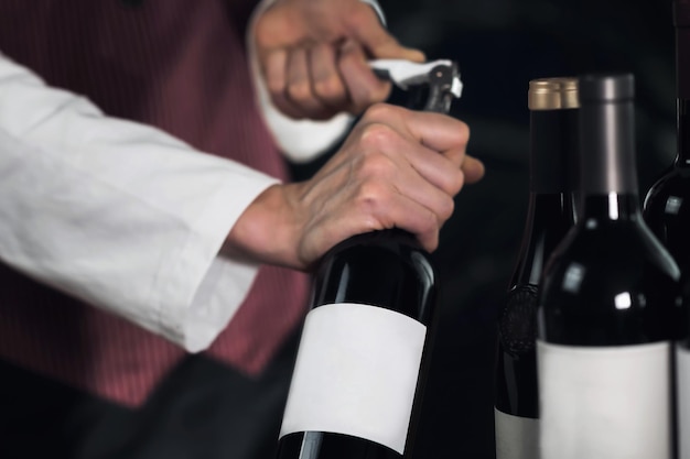 Female sommelier opening wine bottle with corkscrew