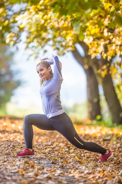 Female sporty young woman doing stretching or warming the body and preparing to jogging.