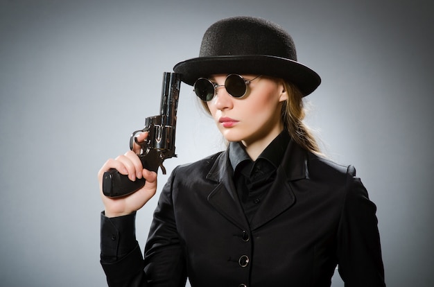 Female spy with weapon against gray