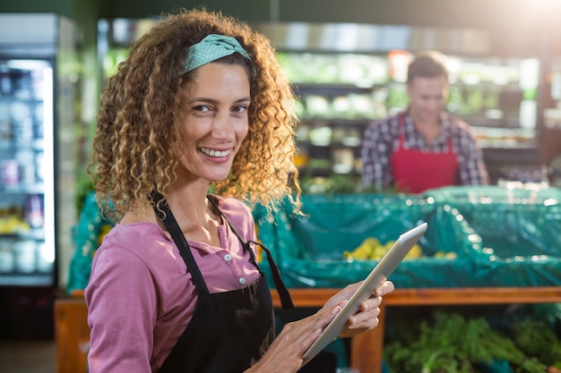 Photo female staff using digital tablet in organic section