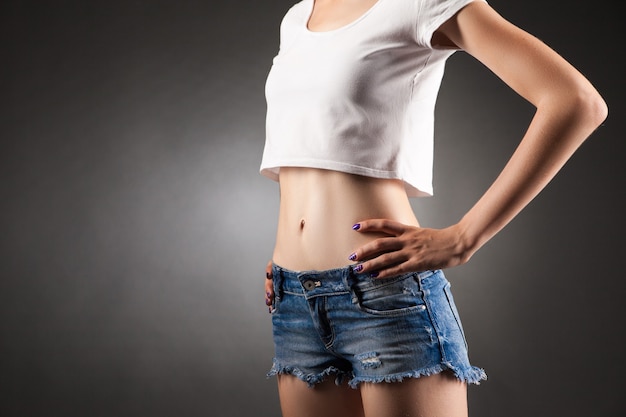 Female, standing akimbo, faceless. Studio portrait black vignette background