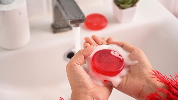Женщина стоит в ванной и использует мыло ручной работы.