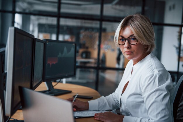 Female stockbroker in formal clothes works in the office with financial market.