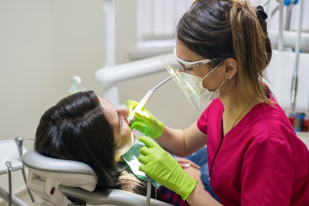 Female stomatologist treating woman's teeth in dental clinic