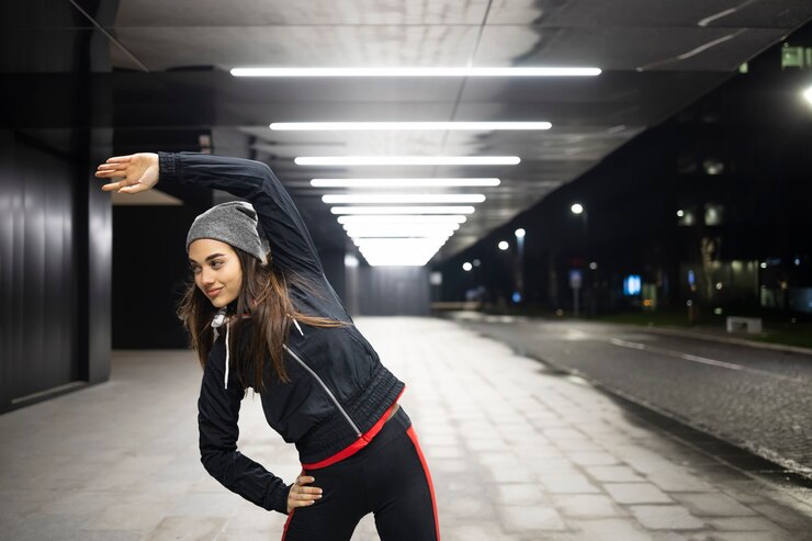 Female stretching her left side before her night jog in the city