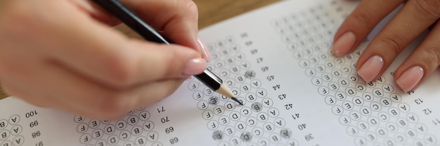 女子生徒が筆でテストの質問に答える 女性がテストの論文で正しい答えを選ぶ