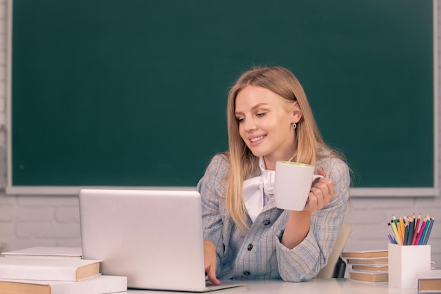 Female student drinking coffee or tea on lesson lecture in classroom at high school or college