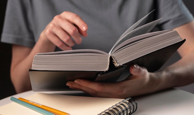 Female student hands close up, pointing on text in book or textbook, searching for information and reading at night