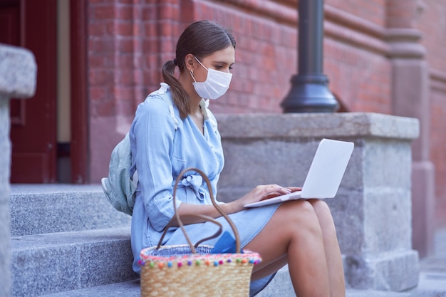 Female student hanging out in the campus wearing protective mask due to coronavirus pandemic