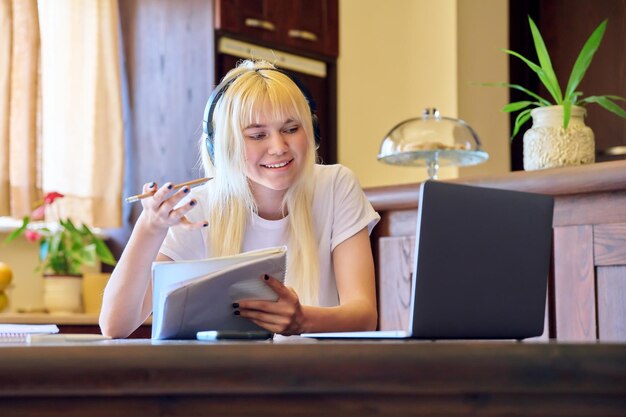 Female student in headphones using a laptop studying at home