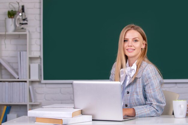 Female student on lesson lecture in classroom at high school or college on blackboard background