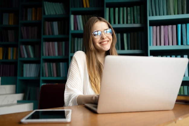 A female student programmer with glasses is working on a\
laptop