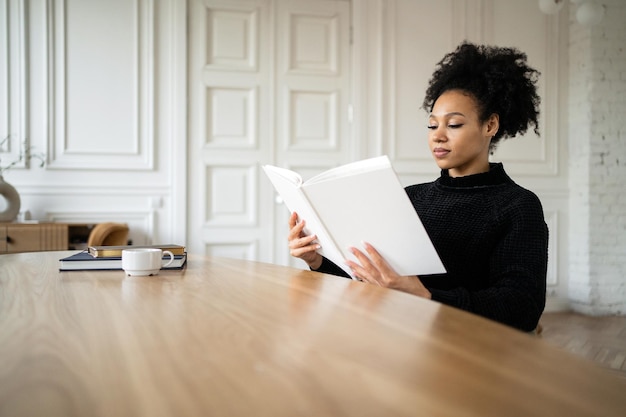 A female student reads a textbook book at home