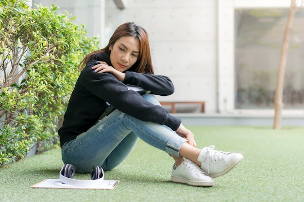 キャンパスの芝生のベンチに座っている女性の学生