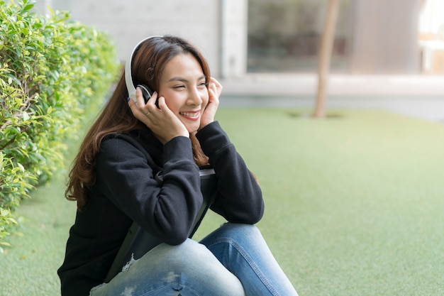 キャンパスの芝生のベンチに座っている女子学生