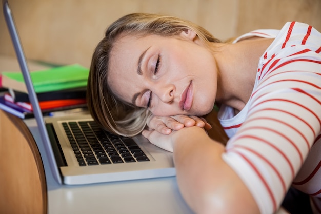 Female student sleeping in class on her laptop at the university