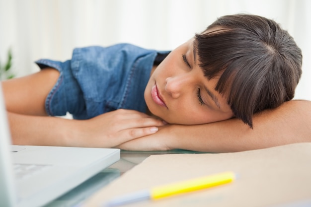 彼女の机の上で眠っている女性の学生