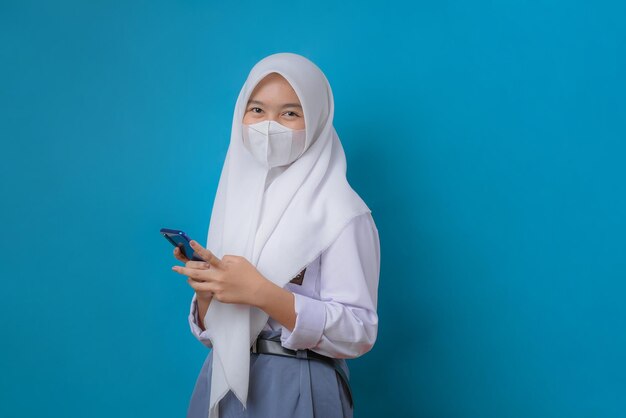 Photo female student using cellular phone wearing face mask studio shot