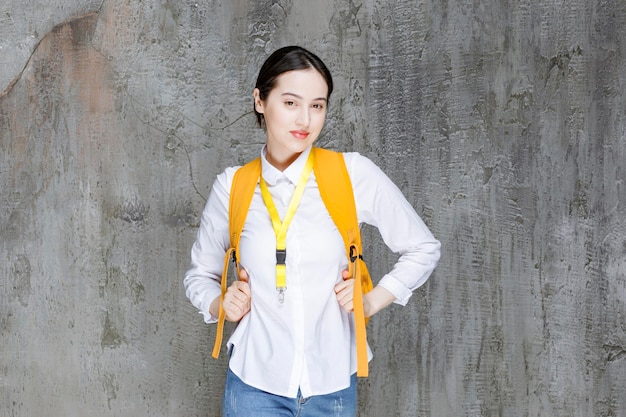 Female student wearing yellow backpack posing. High quality photo